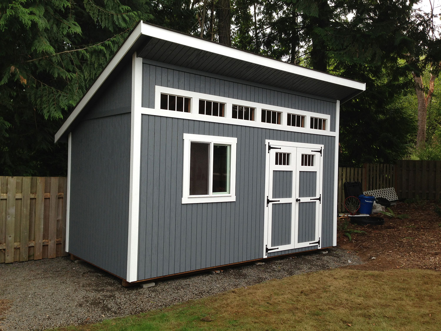 Custom blue-gray storage building with white trim and double doors